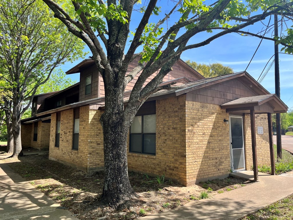 a brick house with a large tree in front of it