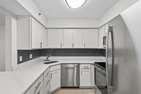 A kitchen with white cabinets and a black backsplash.