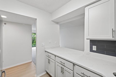 A kitchen with white cabinets and a white counter top.