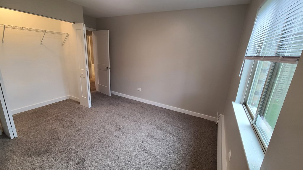 an empty room with a closet and a window