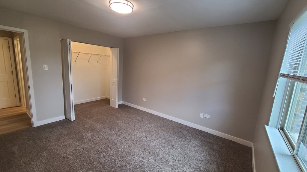 an empty room with a door to a closet and a window