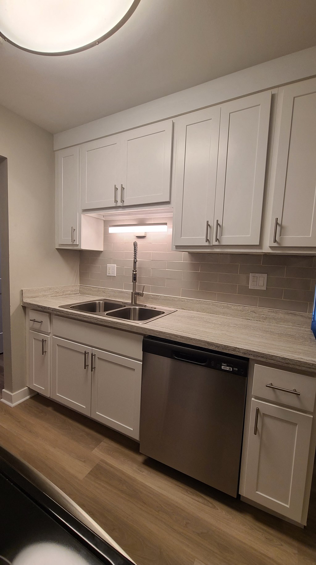 Rehabbed kitchen with white cabinets and glass backsplash