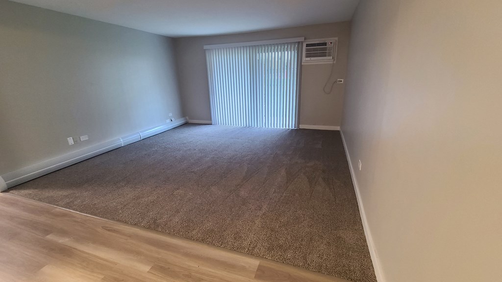 a living room with a window and a carpeted floor