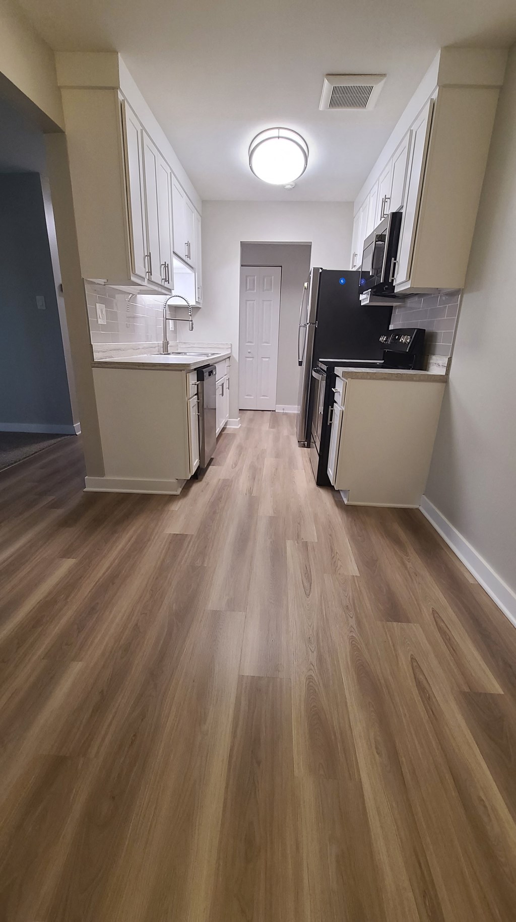 a kitchen and living room with wood floors and white cabinets