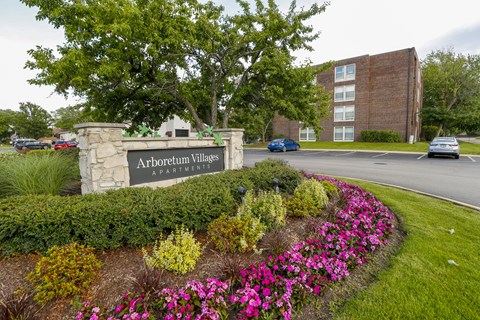 A sign for Arboretum Apartments is in front of a brick building.