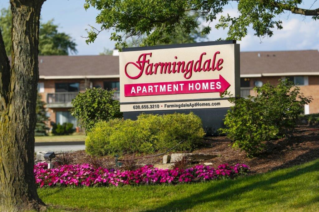 a sign for farmingdale apartment homes with flowers around it