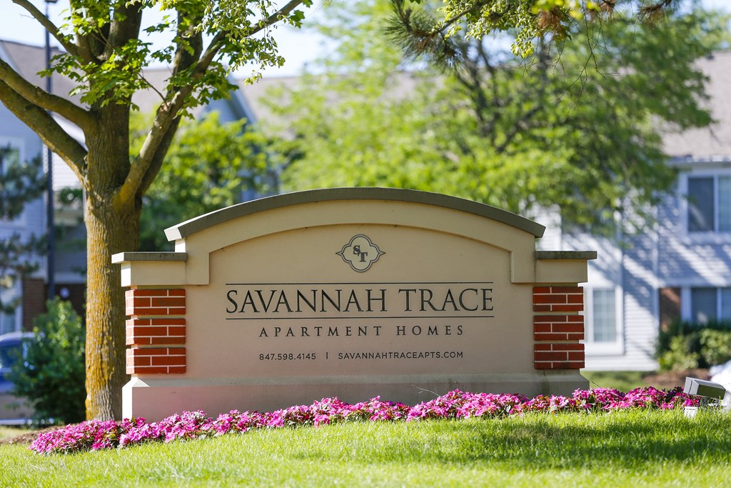 a sign for savannah trace apartment homes in front of a tree