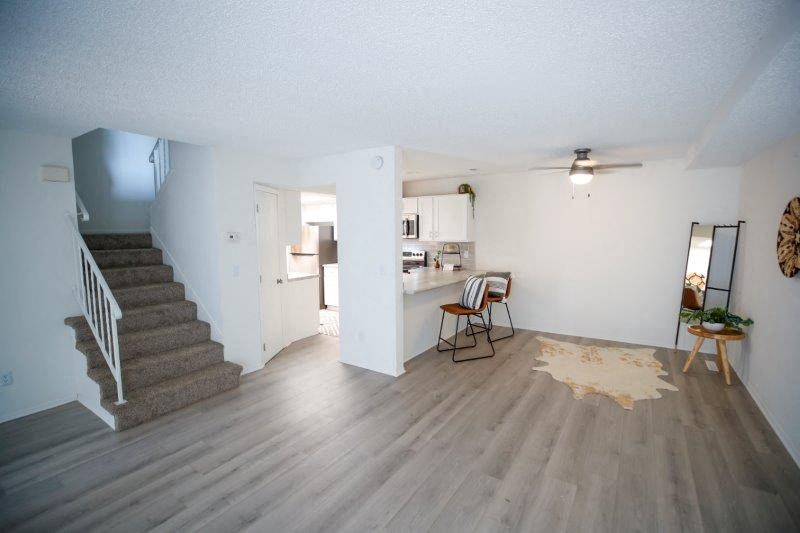 an empty living room with a staircase and a kitchen