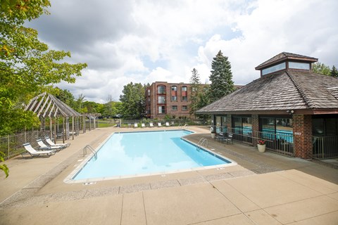 A large outdoor swimming pool surrounded by a fence and trees.