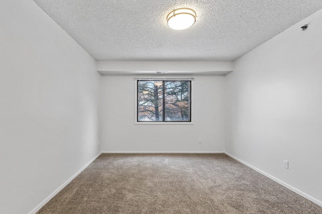 a bedroom with white walls and a large window