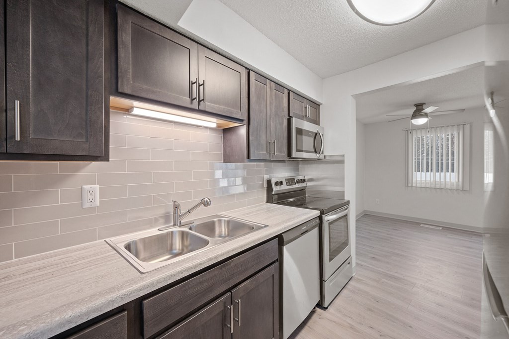 an empty kitchen with stainless steel appliances and wooden cabinets