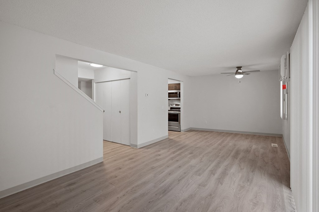 an empty living room with white walls and a ceiling fan