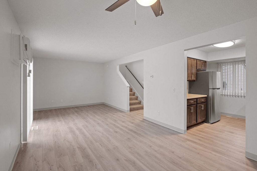 the living room and kitchen of an apartment with wood flooring