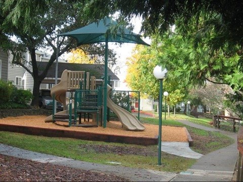 a playground with a slide and umbrella in a park