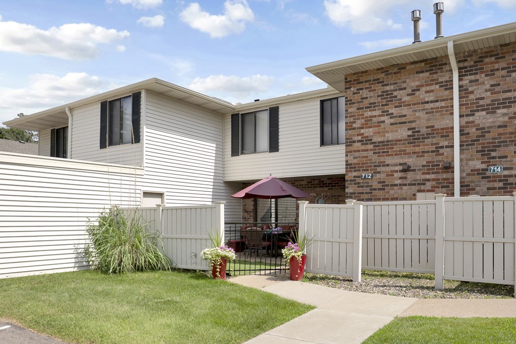 A house with a white fence and a patio with a table and chairs.
