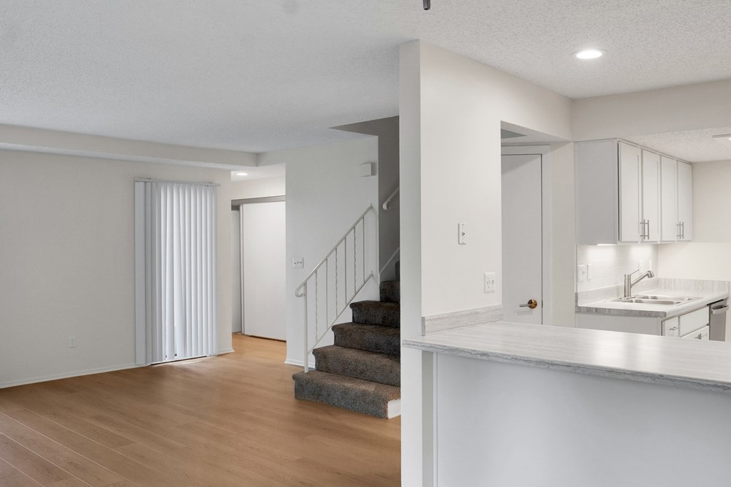 A white room with a staircase and a kitchen area.