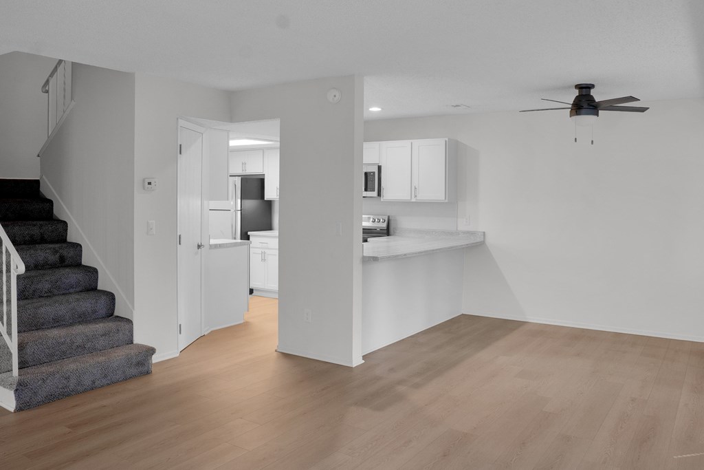 A spacious kitchen and living room with a staircase on the left side.