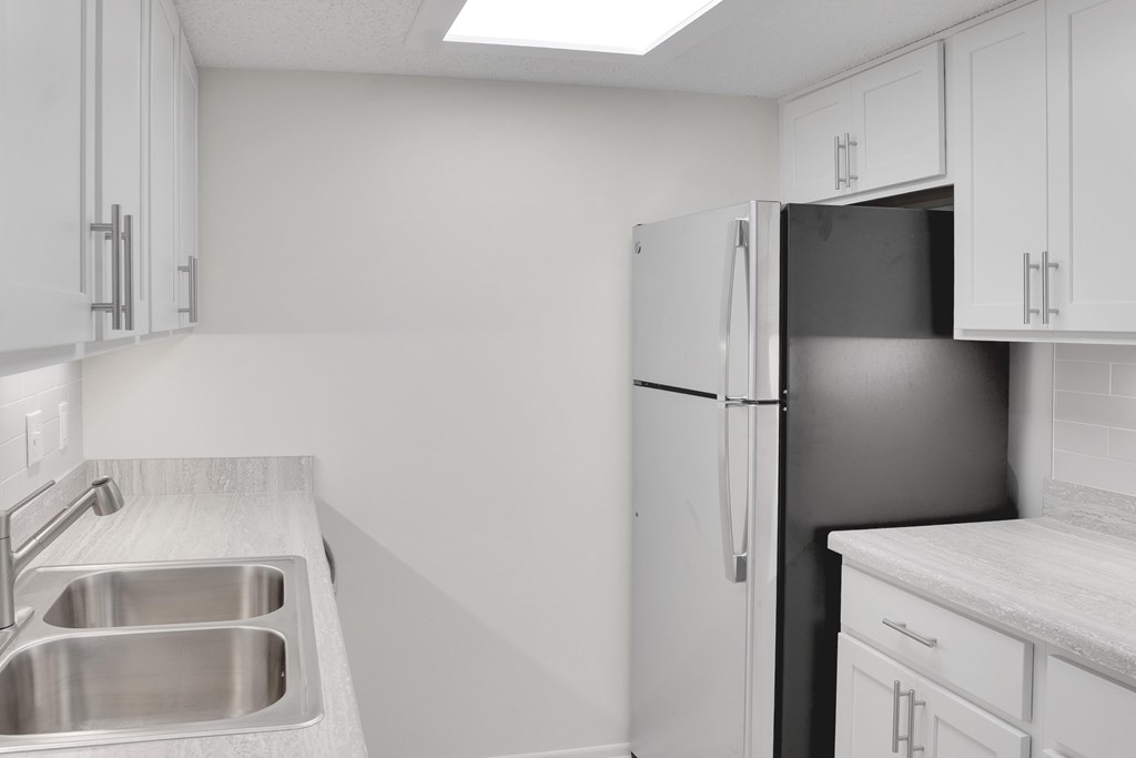 A kitchen with a sink, refrigerator, and cabinets.