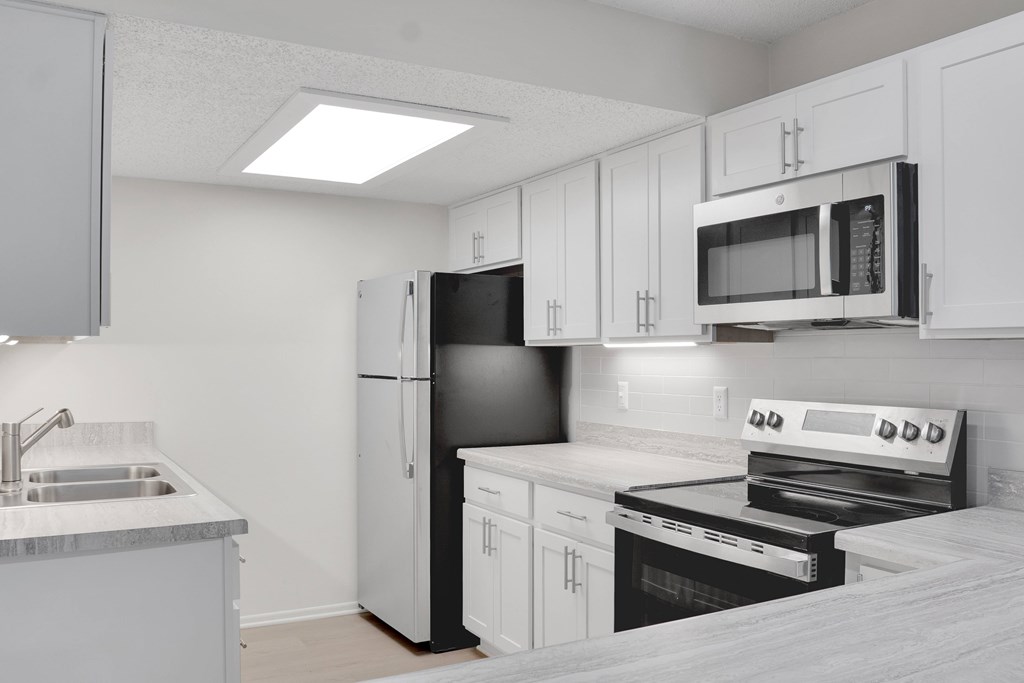 A kitchen with white cabinets and appliances.