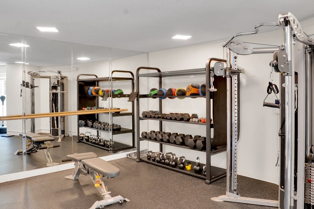 A gym with a variety of equipment including weights and a leg press machine.