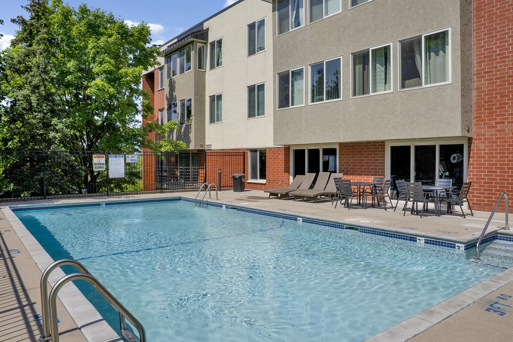 A swimming pool in front of a multi-story apartment building.