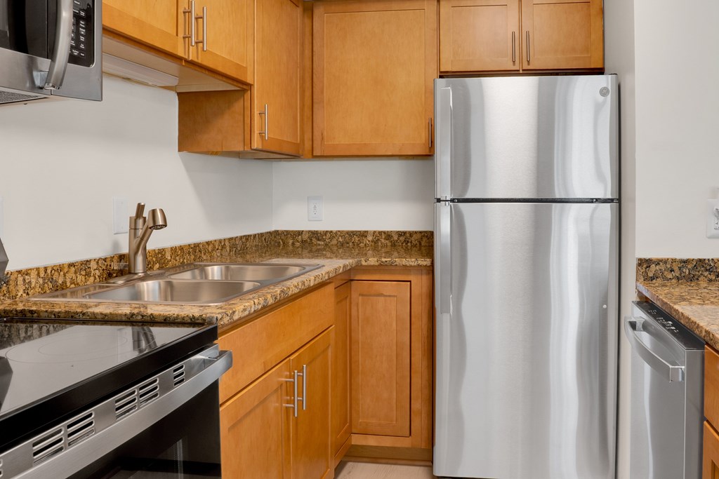 A kitchen with a stainless steel refrigerator and wooden cabinets.