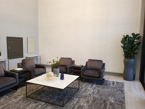A living room with a white coffee table and brown chairs.