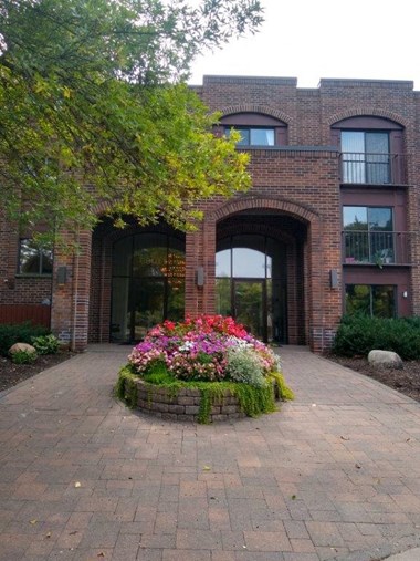 a large brick building with a flower garden in front of it