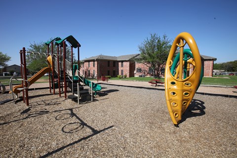 a playground with a seesaw and other playground equipment in front of a building