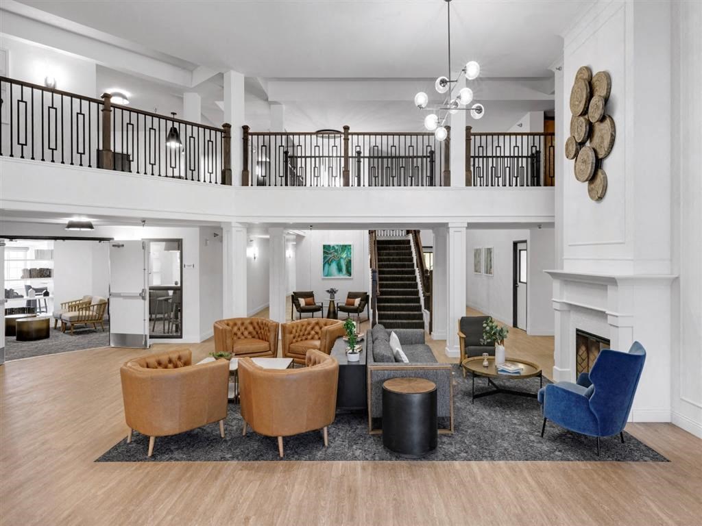 a shared common area with chairs, fireplace, stairway, and balcony.