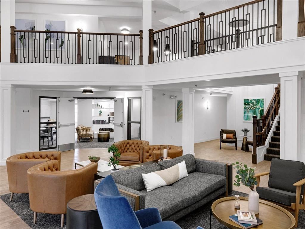 a living room with couches and chairs and a staircase