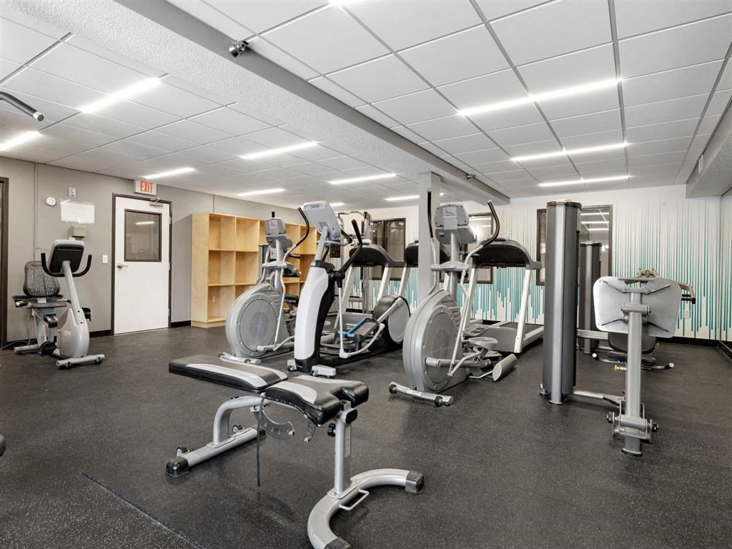 a gym with cardio equipment and weights on the floor
