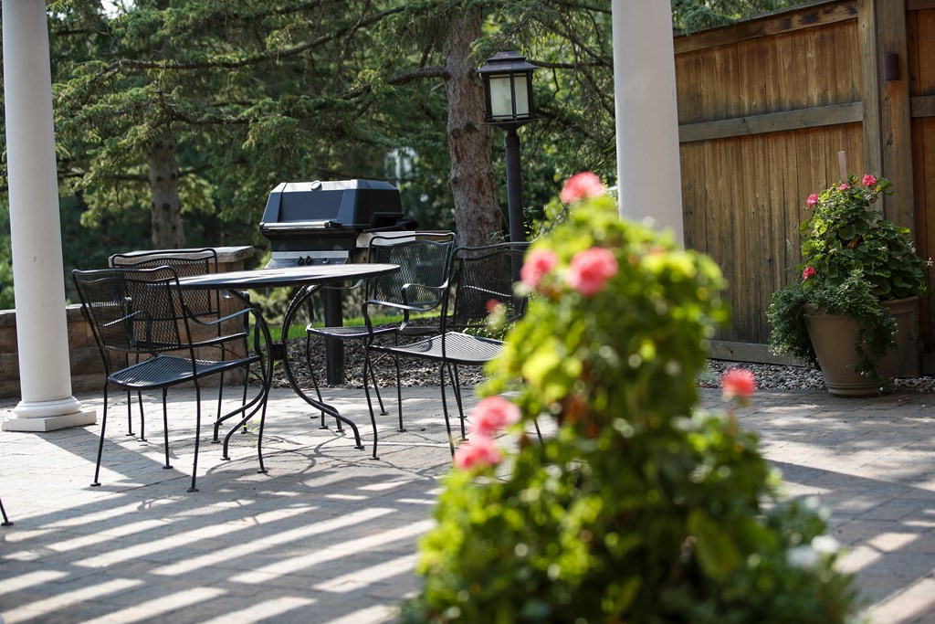 a patio with tables and chairs and an outdoor grill