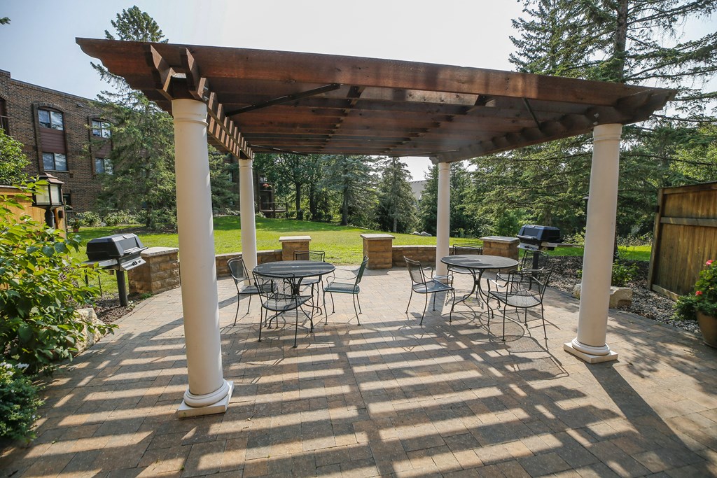 a covered patio with tables and chairs and a pergola