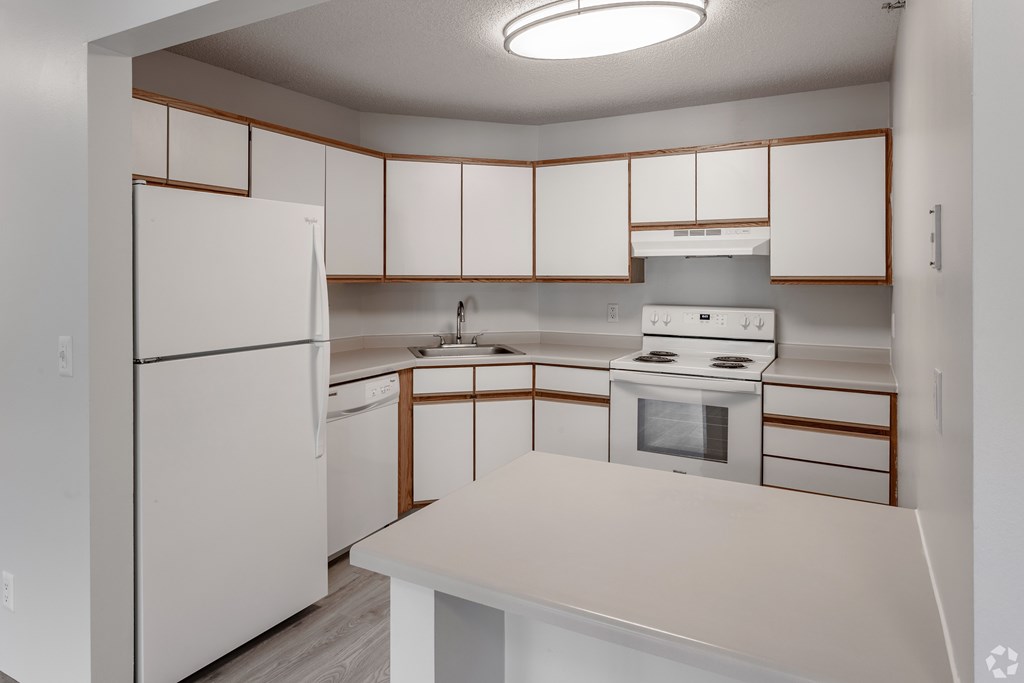 A white kitchen with a refrigerator, oven, and microwave.