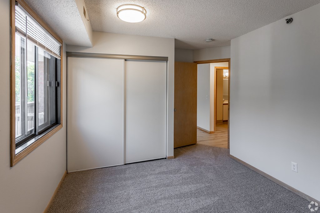 A room with a carpeted floor, a white wall, and a sliding door.