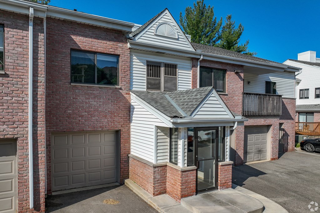A house with a grey garage door and a brick wall.