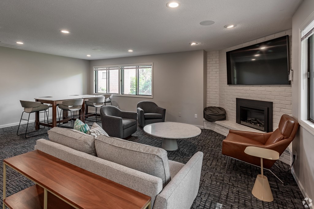 A living room with a grey couch, a brown chair, a white table, and a fireplace.