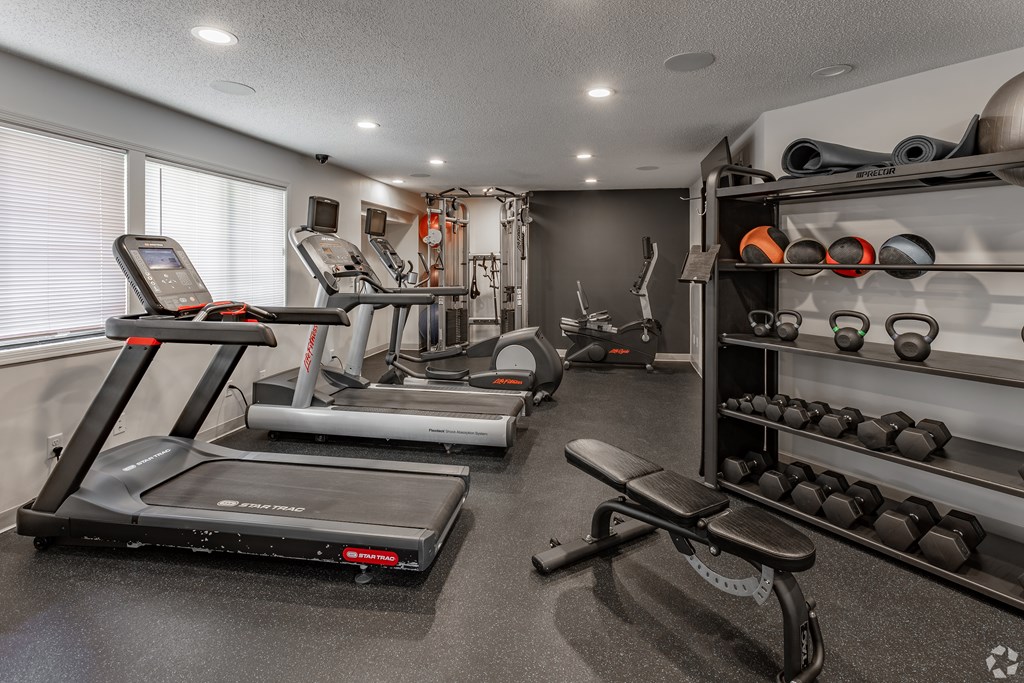 A home gym with a treadmill, weights, and exercise equipment.