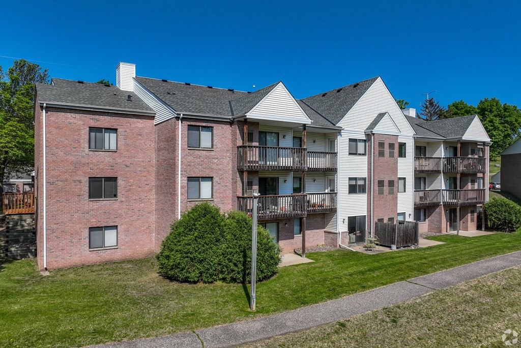 Apartment complex with red brick building and white building with balconies.