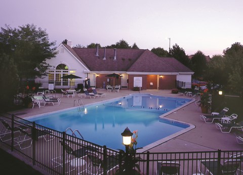 A pool and patio area of a house with a lamp post in the foreground.