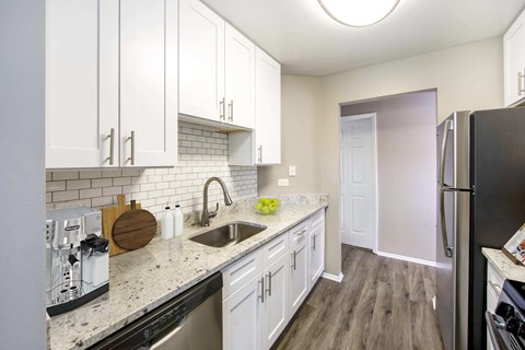 A kitchen with white cabinets and a black refrigerator.