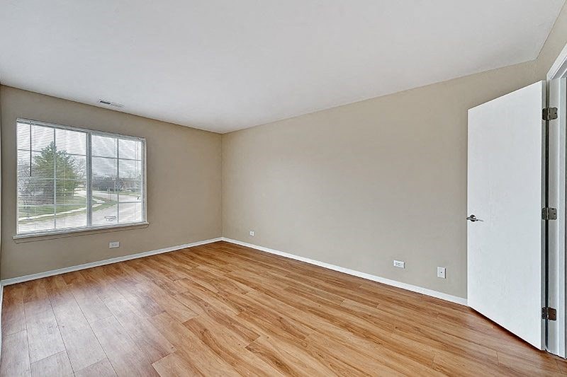 an empty living room with wood floors and a window