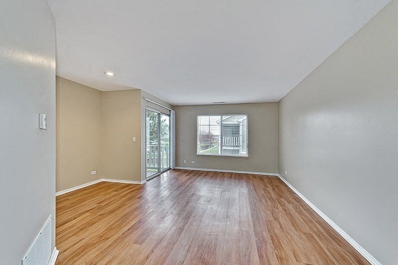 an empty living room with wood floors and a window