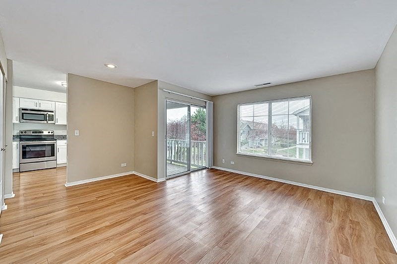 an empty living room with wood flooring and a sliding glass door