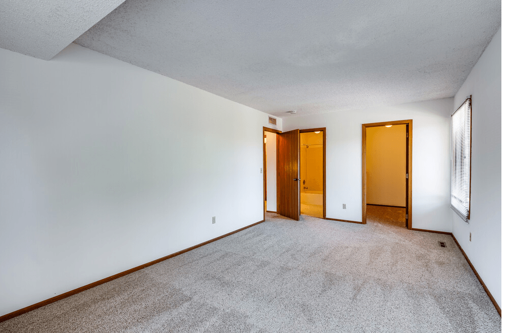 an empty living room with white walls and carpet