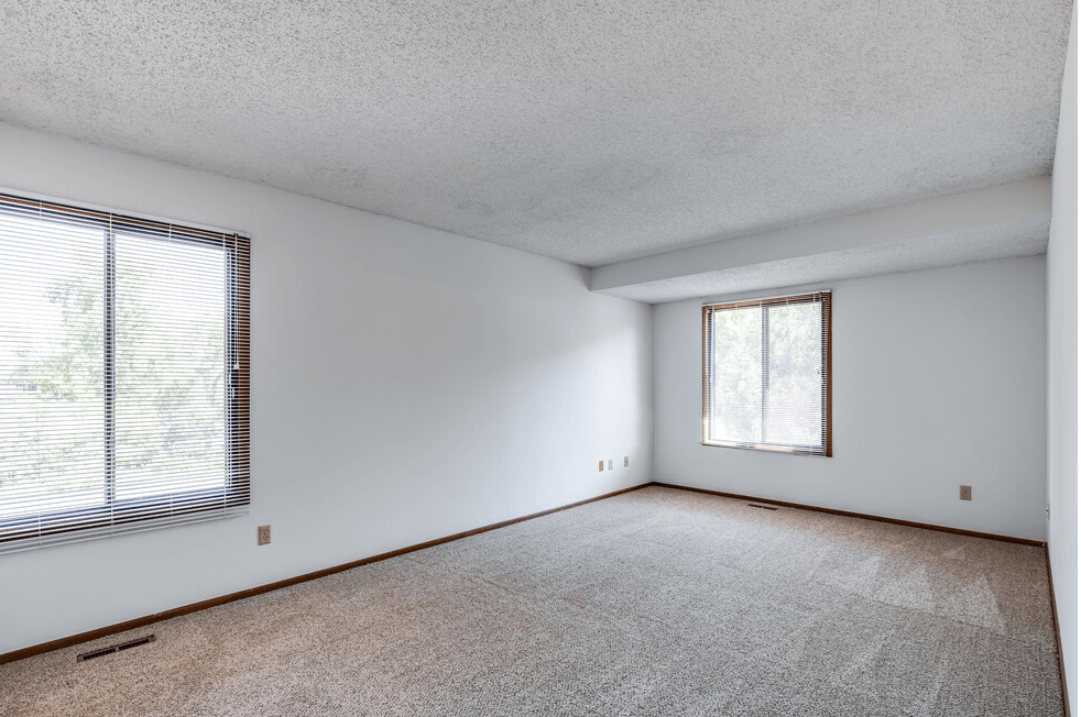 an empty living room with a large window and white walls