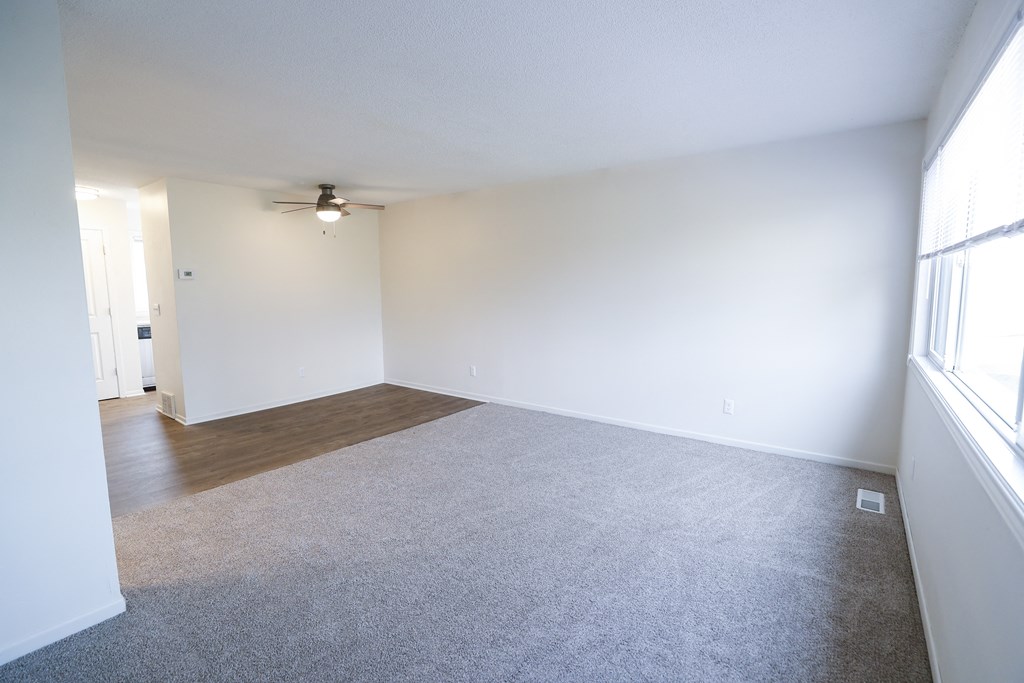 an empty living room with white walls and a ceiling fan