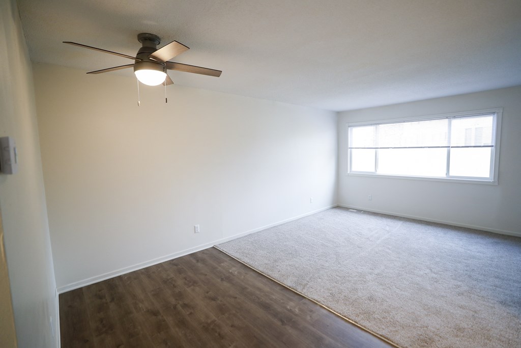 an empty room with a ceiling fan and a window