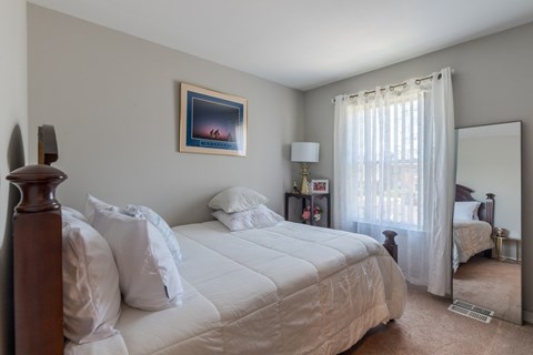A bedroom with a large bed and a painting on the wall.